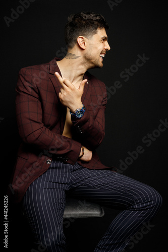 Portrait of an casual man sitting on the chair, simile, Stylish businessman, Portrait of the beautiful posing in a Studio, Black background, Stylish man