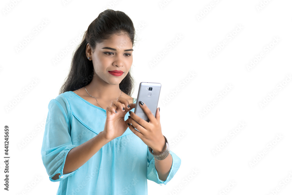Young Indian girl using a mobile phone or smartphone isolated on a white background Young Indian girl using a mobile phone or smartphone isolated on a white background