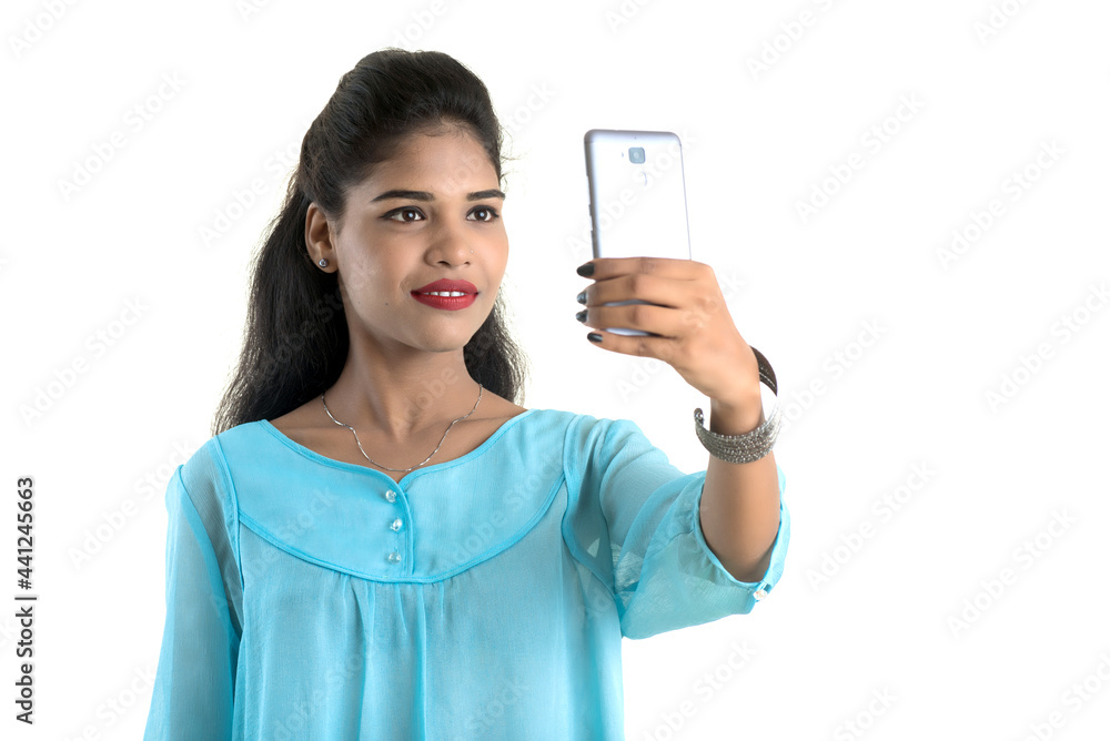 Young Indian girl using a mobile phone or smartphone isolated on a white background Young Indian girl using a mobile phone or smartphone isolated on a white background