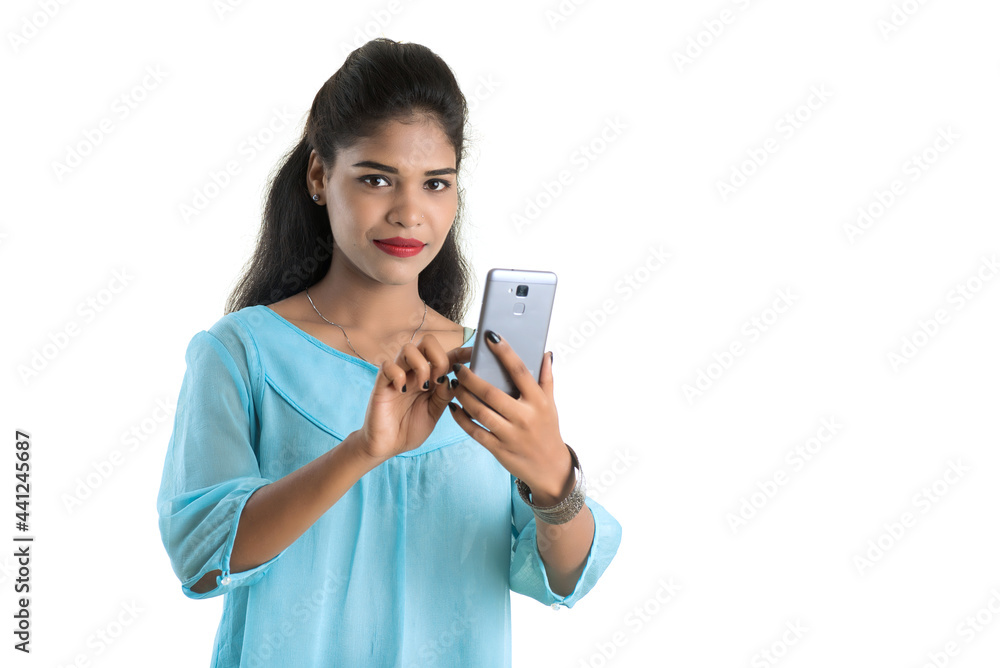 Young Indian girl using a mobile phone or smartphone isolated on a white background Young Indian girl using a mobile phone or smartphone isolated on a white background