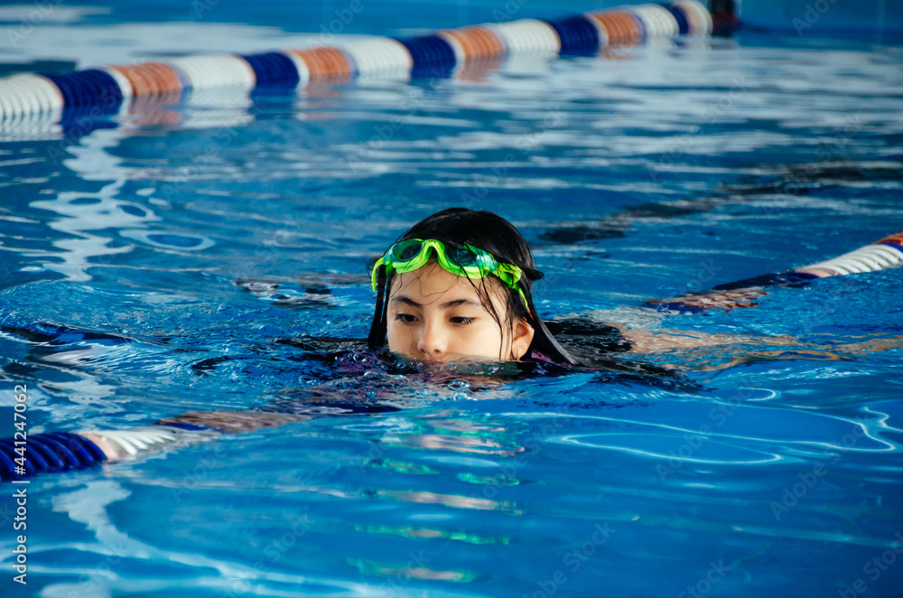 Closeup portrait of cute little peruvian girl swimming in the pool, happy child having fun in water.