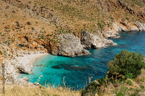 Beach vacation in Sicily,Italy, turquoise water,empty sandy beach in Zingaro Nature Reserve.Holiday paradise travel scenery.Scenic coastline with rocks.Small blue lagoon,clear water,idyllic swimming