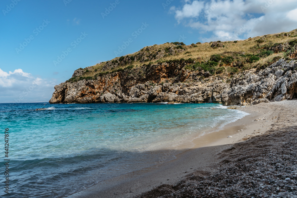 Beach vacation in Sicily,Italy, turquoise water,empty sandy beach in Zingaro Nature Reserve.Holiday paradise travel scenery.Scenic coastline with rocks.Hidden blue lagoon,clear water,idyllic swimming