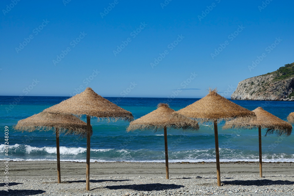 Straw umbrellas on the shore of an Andalusian Mediterranean beach