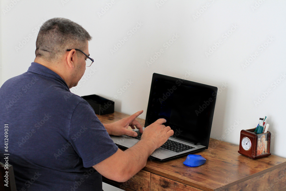 Man working from his home office with grey laptop Man working from his home office with grey laptop