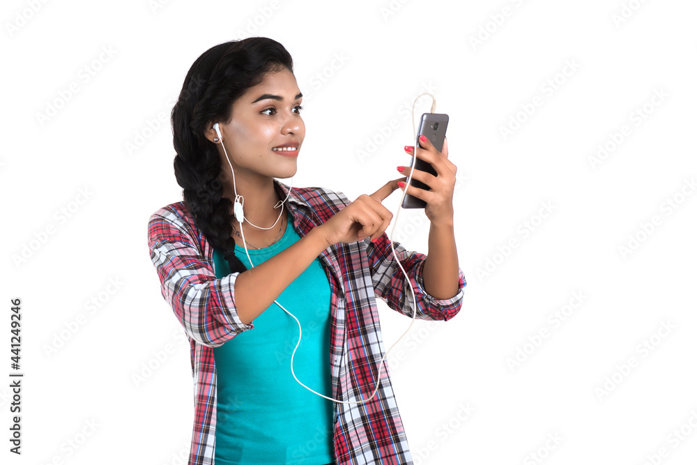 Young Indian girl using a mobile phone or smartphone isolated on a white background Young Indian girl using a mobile phone or smartphone isolated on a white background
