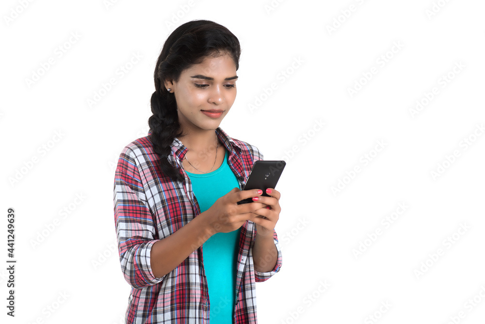 Young Indian girl using a mobile phone or smartphone isolated on a white background Young Indian girl using a mobile phone or smartphone isolated on a white background