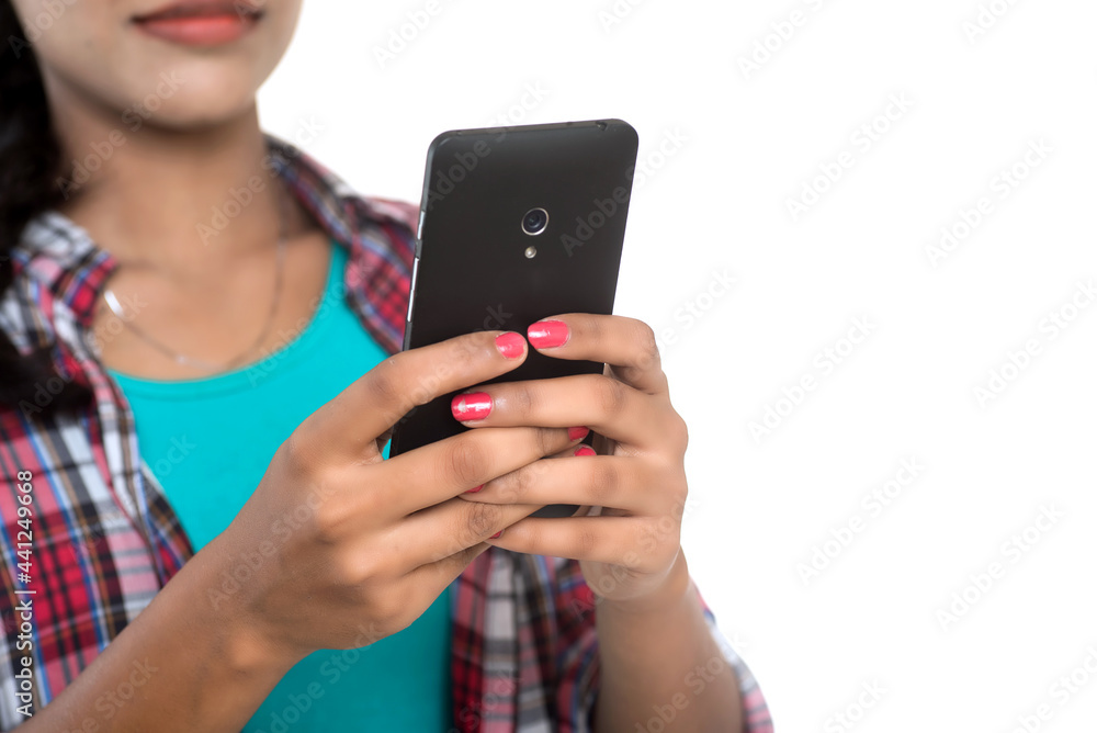 Young Indian girl using a mobile phone or smartphone isolated on a white background Young Indian girl using a mobile phone or smartphone isolated on a white background