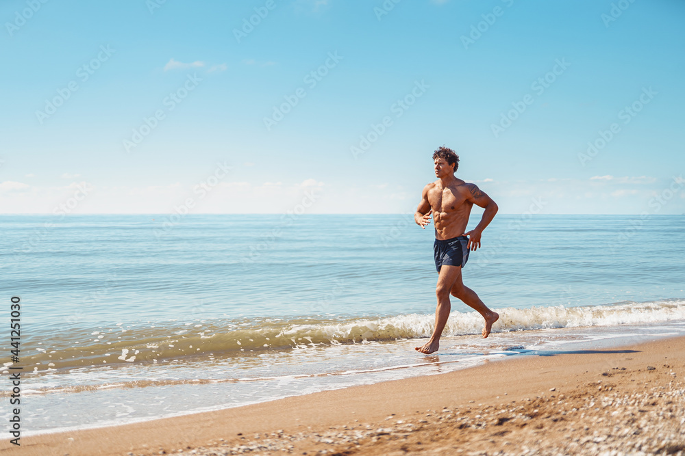 Young muscular guy, with a bare torso running along the beach Young muscular guy, with a bare torso running along the beach