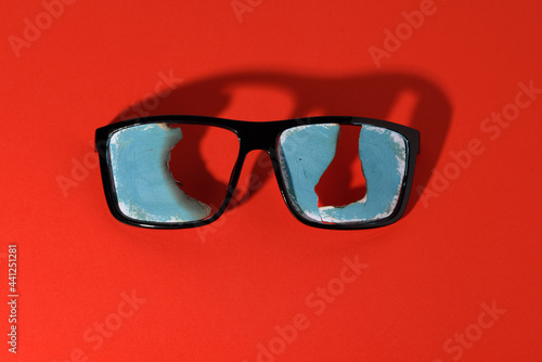 Summer concept of rest and fun. Sunglasses decorated with red paper. Isolated in red.