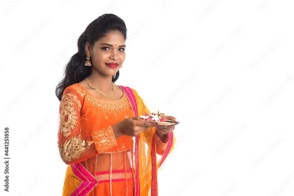 Beautiful Indian young girl holding pooja thali or performing worship on a white background Beautiful Indian young girl holding pooja thali or performing worship on a white background