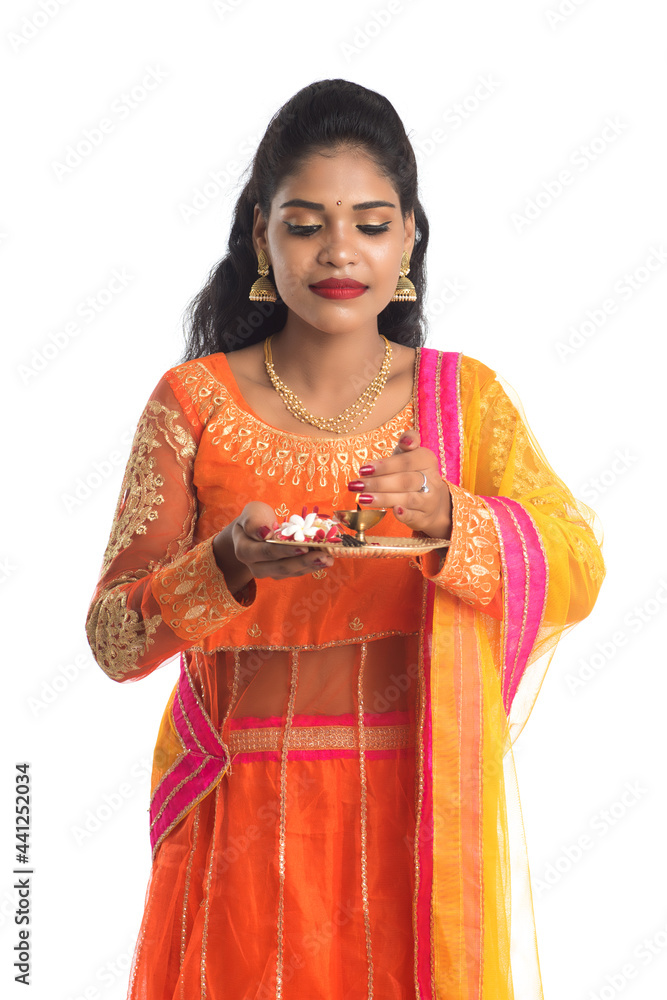 Beautiful Indian young girl holding pooja thali or performing worship on a white background