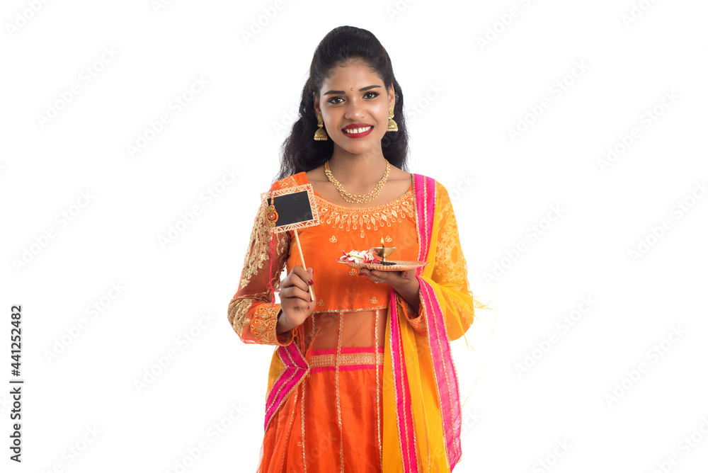 Beautiful Indian girl showing Rakhi on occasion of Raksha Bandhan with pooja thali and black board. Sister tie Rakhi as a symbol of intense love for her brother.