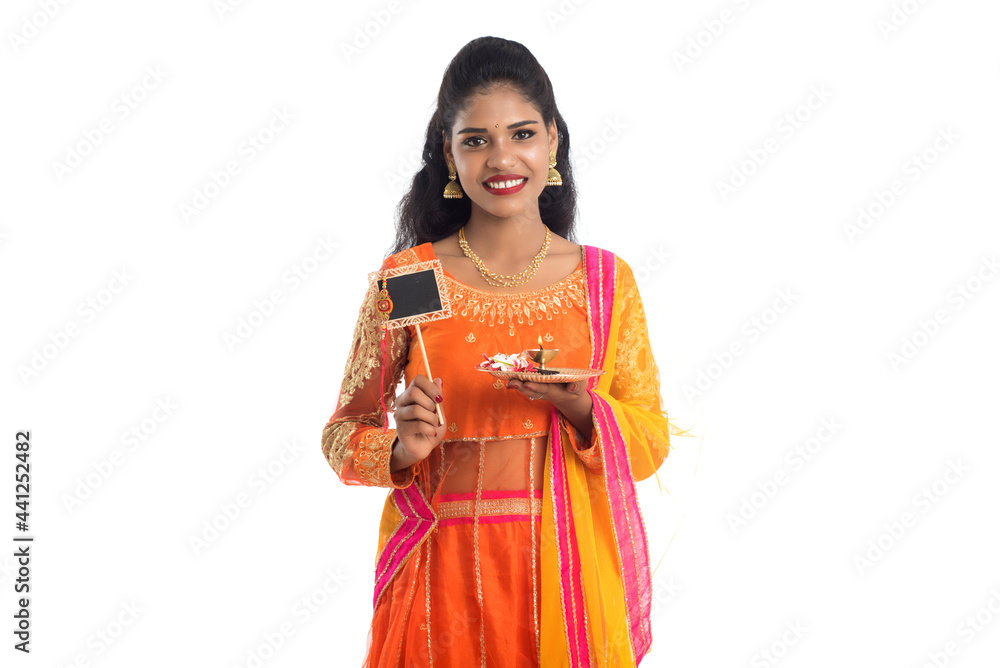 Beautiful Indian girl showing Rakhi on occasion of Raksha Bandhan with pooja thali and black board. Sister tie Rakhi as a symbol of intense love for her brother. Beautiful Indian girl showing Rakhi on occasion of Raksha Bandhan with pooja thali and black board. Sister tie Rakhi as a symbol of intense love for her brother.