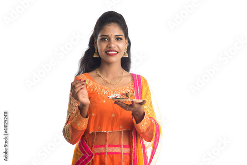 Beautiful Indian young girl holding pooja thali or performing worship on a white background