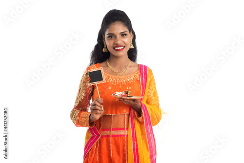 Beautiful Indian girl showing Rakhi on occasion of Raksha Bandhan with pooja thali and black board. Sister tie Rakhi as a symbol of intense love for her brother.