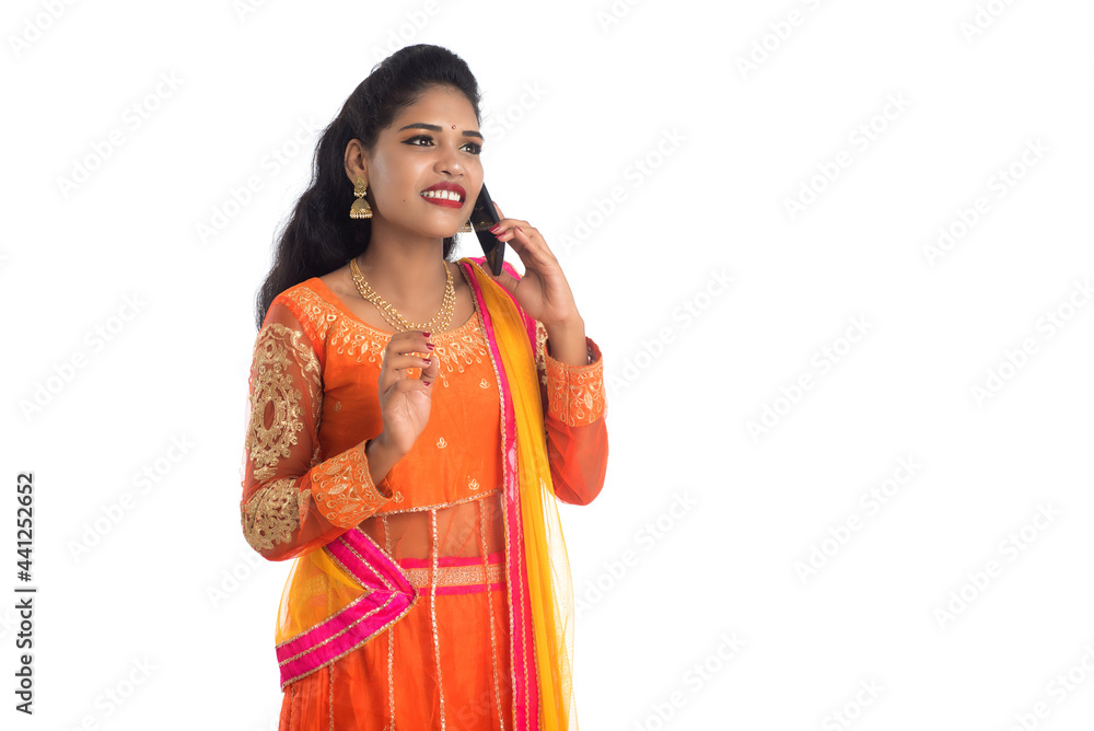 Young Indian traditional girl using a mobile phone or smartphone isolated on a white background Young Indian traditional girl using a mobile phone or smartphone isolated on a white background