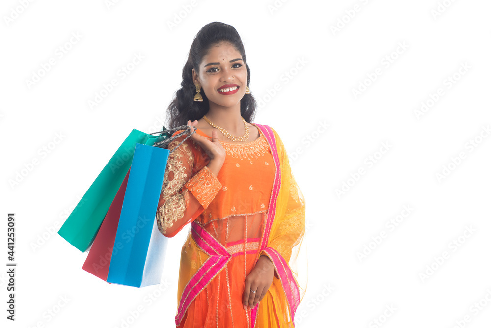 Beautiful Indian young girl holding shopping bags while wearing traditional ethnic wear. Isolated on a white background Beautiful Indian young girl holding shopping bags while wearing traditional ethnic wear. Isolated on a white background