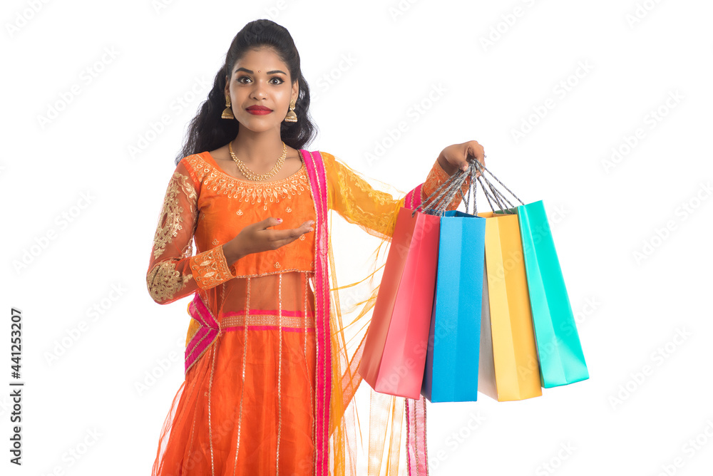 Beautiful Indian young girl holding shopping bags while wearing traditional ethnic wear. Isolated on a white background Beautiful Indian young girl holding shopping bags while wearing traditional ethnic wear. Isolated on a white background