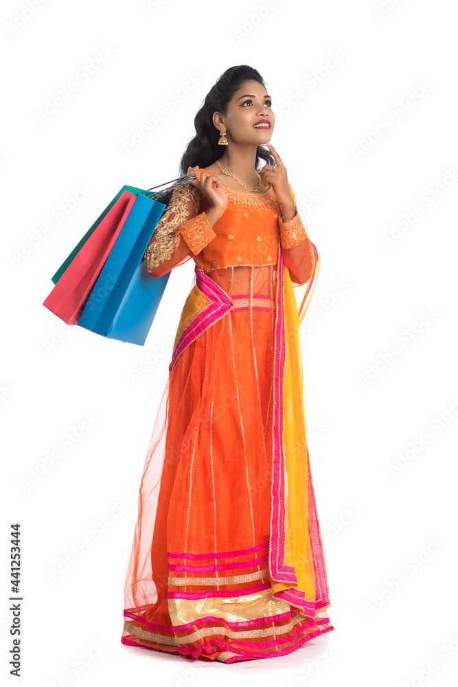 Beautiful Indian young girl holding shopping bags while wearing traditional ethnic wear. Isolated on a white background Beautiful Indian young girl holding shopping bags while wearing traditional ethnic wear. Isolated on a white background