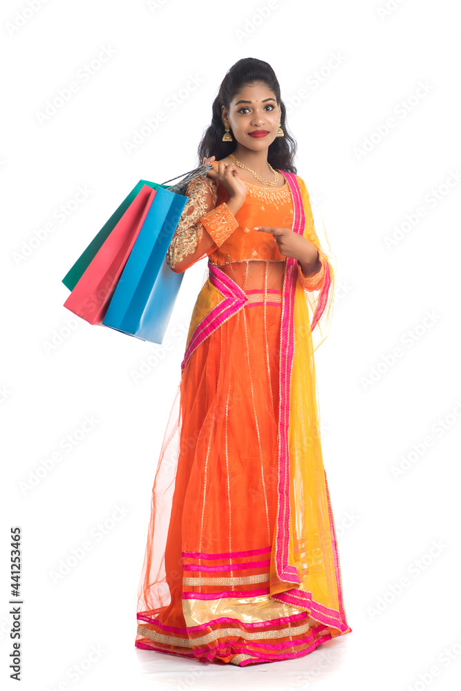 Beautiful Indian young girl holding shopping bags while wearing traditional ethnic wear. Isolated on a white background