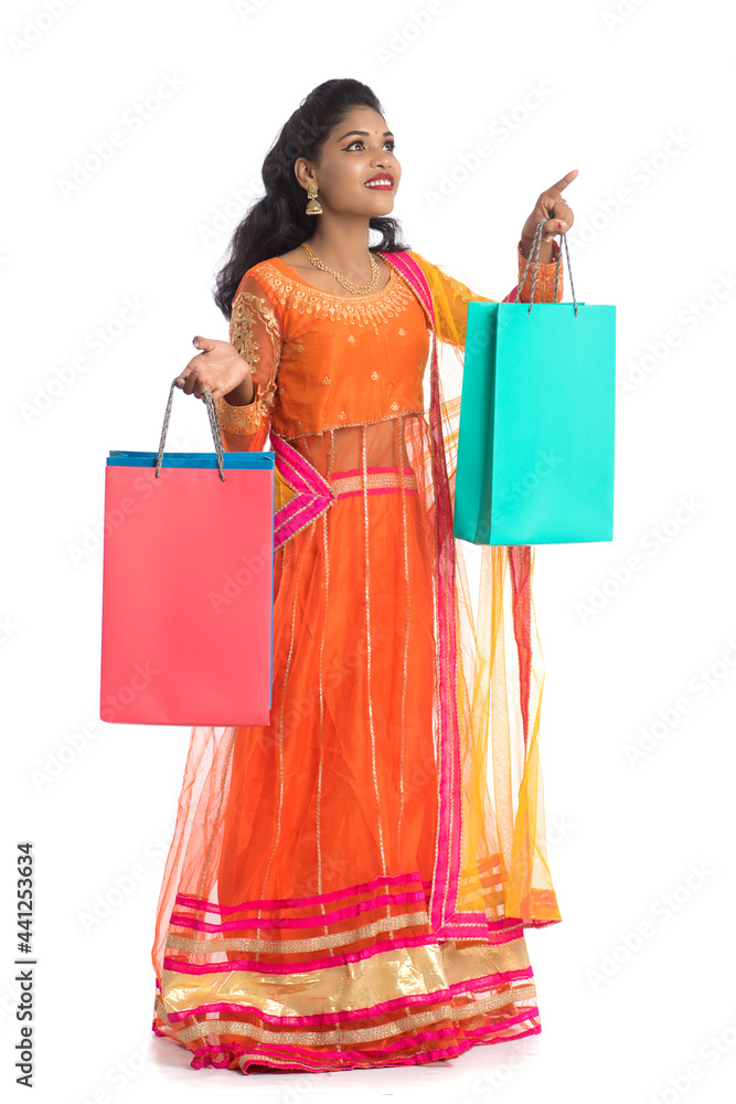 Beautiful Indian young girl holding shopping bags while wearing traditional ethnic wear. Isolated on a white background Beautiful Indian young girl holding shopping bags while wearing traditional ethnic wear. Isolated on a white background