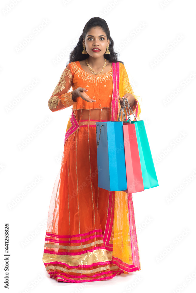 Beautiful Indian young girl holding shopping bags while wearing traditional ethnic wear. Isolated on a white background