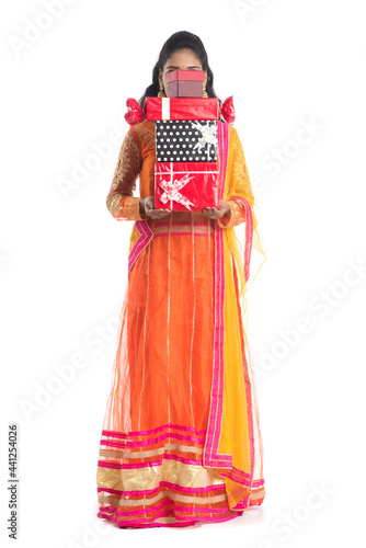 Portrait of young happy smiling Indian Girl holding gift boxes on a white background.