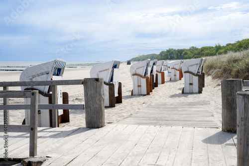 Fototapeta Naklejka Na Ścianę i Meble -  White beach chairs on light sand on a wooden jetty on the Mecklenburg coast, Western Pomerania