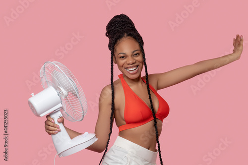 Smiling african american woman holding a fan and looking enjoyed