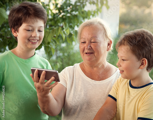 cute little boy using smartphone with grandma at home veranda