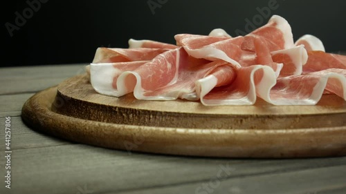 Italian prosciutto crudo, wooden plate of raw ham, cold cuts video slow motion photo