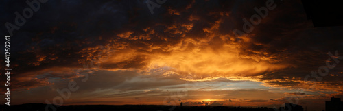 High resolution stormy sunset panorama. Epic clouds highlighted gold by setting sun.