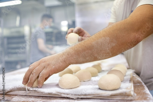 Baker makes bread and buns for baking it