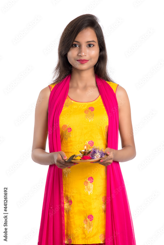 Beautiful Indian young girl holding pooja thali or performing worship on a white background Beautiful Indian young girl holding pooja thali or performing worship on a white background
