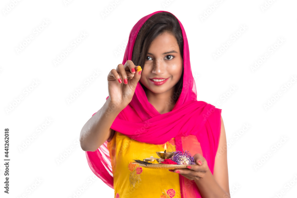 Beautiful Indian young girl holding pooja thali or performing worship on a white background Beautiful Indian young girl holding pooja thali or performing worship on a white background