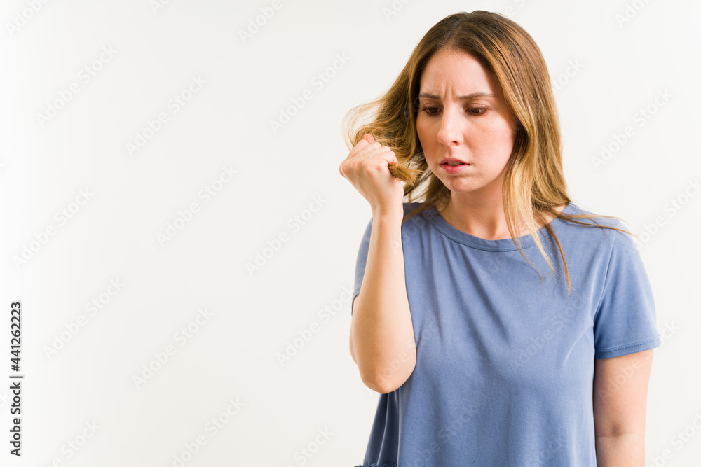 Worried woman checking her unhealthy hair Worried woman checking her unhealthy hair