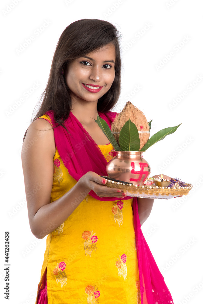 Indian girl holding a traditional copper Kalash with Pooja Thali, Indian Festival, copper Kalash with coconut and mango leaf with floral decoration, essential in Hindu Pooja.