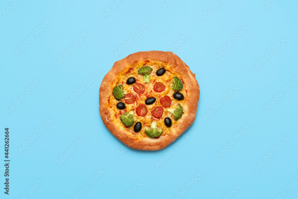 Fototapeta Vegan pizza isolated on blue table. Homemade vegetable pizza, top view