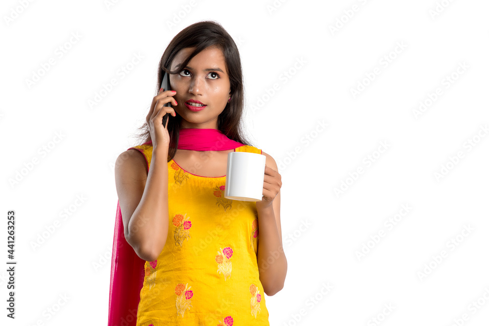 Pretty young girl calling on smartphone device while drinking tasty coffee or tea beverage Pretty young girl calling on smartphone device while drinking tasty coffee or tea beverage