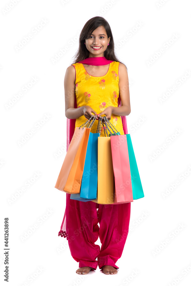 Beautiful Indian young girl holding and posing with shopping bags on a white background Beautiful Indian young girl holding and posing with shopping bags on a white background