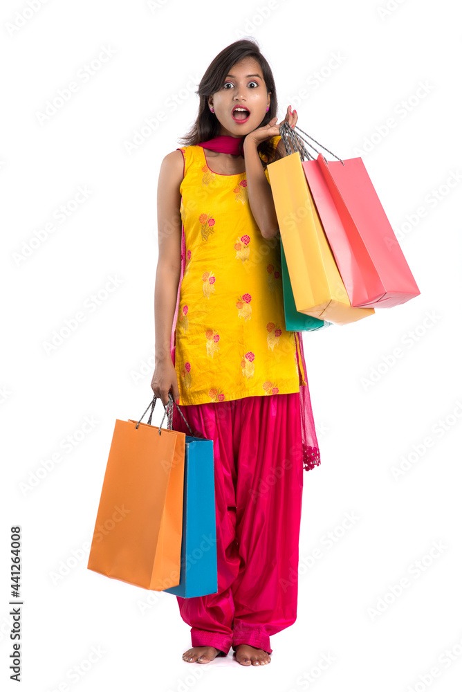 Beautiful Indian young girl holding and posing with shopping bags on a white background Beautiful Indian young girl holding and posing with shopping bags on a white background