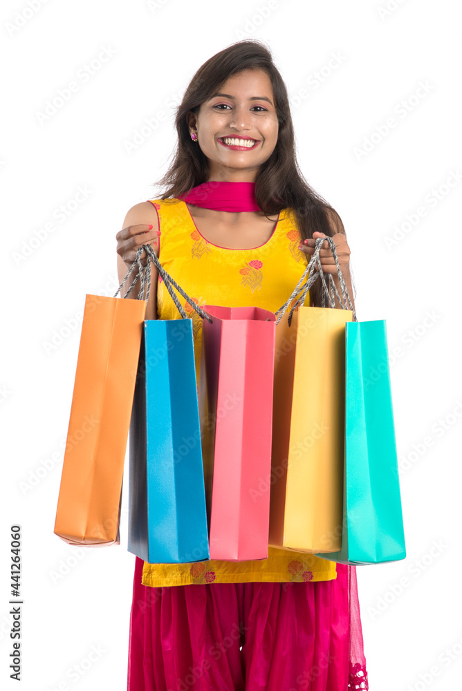 Beautiful Indian young girl holding and posing with shopping bags on a white background Beautiful Indian young girl holding and posing with shopping bags on a white background