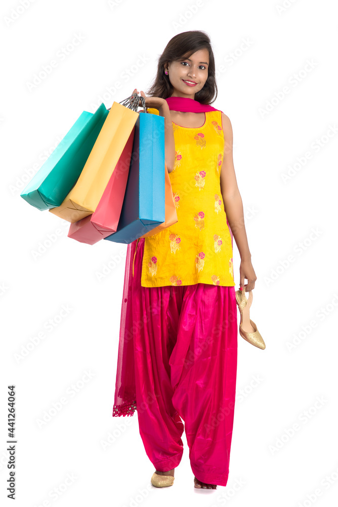 Beautiful Indian young girl holding and posing with shopping bags on a white background Beautiful Indian young girl holding and posing with shopping bags on a white background