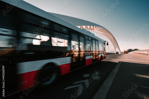 Blurred red passenger bus in motion going over bridge during sunrise