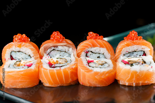 Roll red dragon with salmon, red caviar, tobiko, eel, rice, nori close-up. Sushi traditional Japanese cuisine.