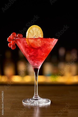 Closeup glass of cosmopolitan cocktail decorated with orange photo