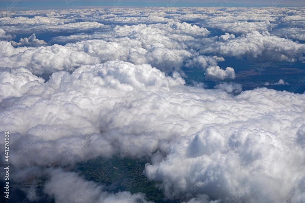 sky with thunderous white clouds above the ground view from the airplane window, horizontal. sky with thunderous white clouds above the ground view from the airplane window, horizontal.