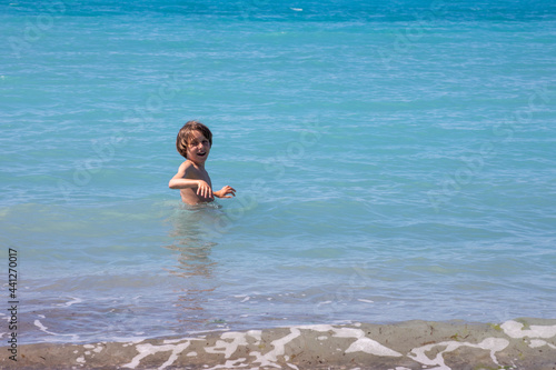 happy boy walks in the vegean sea on vacation, sunny day,.