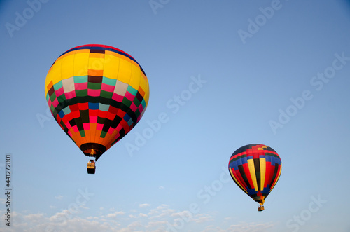 Hot air balloons in a blue sky with clouds. © Cris Alexakis
